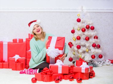 Heyecanlı sarışın, elinde fiyonklu bir hediye kutusu tutuyor. Kız arkadaş ya da eş için mükemmel bir hediye. Noel hediyesini açıyorum. Noel ağacının yanındaki kız bayramı kutluyor. Ona her zaman istediği hediyeyi ver.