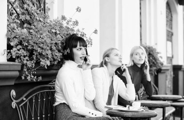 Dijital cihazlar kullanarak. Grup kadın kafe terası. Arkadaşlık toplantısı. Mobil bağımlısı. Gezici konuşma. Cep telefonu olan kızlar. Arkadaşlar kafeteryada oturup konuşmanın tadını çıkarırlar. Konuşmaya takıntılı.