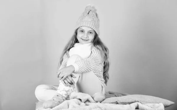 어린이의 긴 머리를 가진 따뜻 한 모직 모자는 따뜻 함을 즐긴다. 따뜻 한 옷 컨셉. 따뜻하고 편안 한 상태를 유지하 십시오. 따뜻 한 액세서리는 이번 겨울을 아늑하게 해 줄 것이다. 여자 애는 분홍빛 배경에 뜨개 질 모자를 쓰고 — 스톡 사진