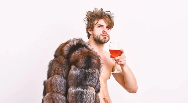 Health and wellbeing. Richness and luxury concept. Rich athlete enjoy his life. Guy attractive rich posing fur coat on naked body. Sexy sleepy rich macho tousled hair drink wine isolated on white — Stock Photo, Image