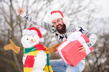 Neşeli hissediyorum. Sakallı adam kardan adam yapar. Kış mevsimi aktivitesi. Mutlu noeller. Noel Baba hediyesini dışarıda verir. Mutlu hipster Noel 'e hazır. Kış tatili Soğuk havada sıcak kazak