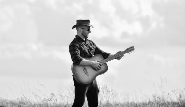 İlham veren country müzisyeni. Yürüyüş şarkısı. Güzel melodi çal. Gitarlı yakışıklı adam. Country tarzı. Yaz tatili. Country müzik konsepti. Gitarist country şarkıcısı alan gökyüzü arka planda standı