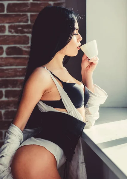 Caffè, portami via. Ragazza sensuale che beve il suo caffè mattutino preferito. Bella donna che beve caffe 'caldo alla finestra. Ragazza sexy che tiene tazza di caffè in ceramica — Foto Stock