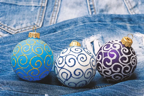 Tres bolas de Navidad decoración pantalones vaqueros fondo. Concepto de vacaciones de invierno. Decora el árbol de Navidad con juguetes tradicionales. El símbolo del nuevo año y las fiestas navideñas. Celebra la Navidad —  Fotos de Stock