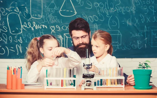 Profesora de biología. El profesor barbudo trabaja con microscopio y tubos de ensayo en el aula de biología. Cómo interesar a los niños a estudiar. Explicar la biología a los niños. Fascinante lección de biología — Foto de Stock