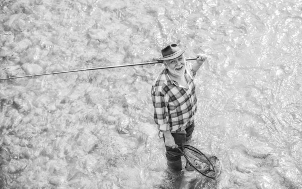 Summer leisure. Fisherman fishing equipment. Hobby sport activity. Fisherman alone stand in river. Fish normally caught in wild. Man bearded fisherman. Weekends made for fishing. Active sunny day