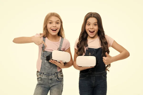 We like this game. Happy little children like playing video games together. Small girls pointing at vr headsets and giving thumb sign of like. Thumbs up if you like it too