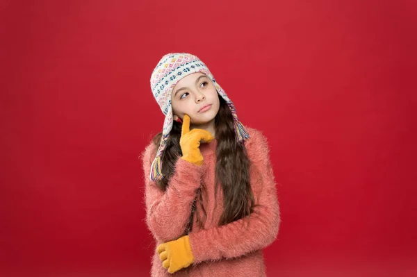 Climate changing. Frosty weather. Winter outfit. Cute model enjoy winter style. Little kid wear knitted hat. Little girl winter fashion accessory. Small child long hair wear hat red background — Stock Photo, Image