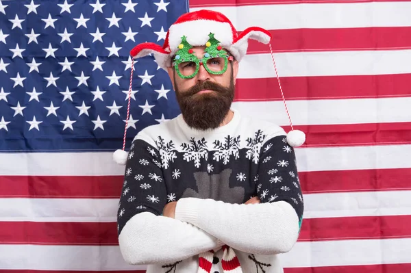 Babbo Natale ti sta guardando. L'uomo barbuto indossa occhiali divertenti. Divertente hipster su sfondo bandiera americana. Divertente ma patriottico. Divertimento invernale. Buon Natale. Ciao. Divertente idea di costume di Capodanno. Festa delle vacanze — Foto Stock