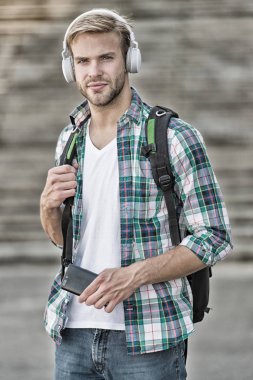 Müziği dinle. Modern ve dijital gençlik. Moda adamı. Üniversite öğrencisi kulaklıkları akıllı telefon. Online eğitim. Ses kitabı konsepti. Eğitim teknolojisi. Öğrenciyim. okul hayatı