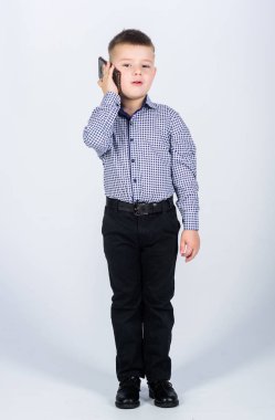 Mobil iletişim. Modern bir alet. Küçük işadamı. İşletme. Yetiştirme ve geliştirme. Küçük çocuk resmi kıyafetler cep telefonunu arıyor. Şirin çocuk akıllı telefonu tut. Mobil konuşma