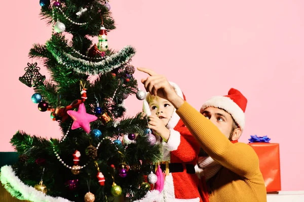 La famiglia di Natale decora abete su sfondo rosa. — Foto Stock