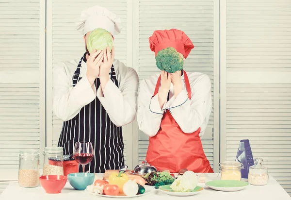 Healthy food concept. Couple cooking healthy vegetarian meal. Vegetarian family. Vegetarian nutrition and vegetable diet. Diet on their mind. Couple cooks hold cabbage and broccoli in front of face