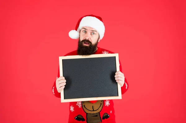 Año nuevo y publicidad navideña. El hombre barbudo tiene un tablero de publicidad en blanco. Santa Claus muestra publicidad escolar. Publicidad y educación, espacio para copias — Foto de Stock