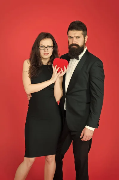 formal couple with red valentine heart. take my heart. one heart for two. sexy woman and mature man with beard. couple in love. formal couple. Love relationship. expert in love. formal fashion expert