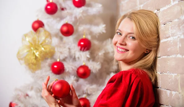 Een vrolijke vrouw die lacht bij de kerstboom. Kerstavond concept. Meisje in rode jurk bij kerstboom met ornamenten. Wachten op kerst. Dingen die je moet doen voordat de feestdagen beginnen Stockfoto