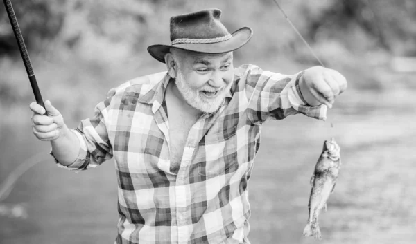 Etwas älter. Schlaglöcher. Mann beim Fischfang. Bartfischer im Ruhestand. Großwildfischen. Reifer Mann angelt. Sport und Hobby. Forellenköder. Sommerwochenende. Fischer mit Angelrute — Stockfoto