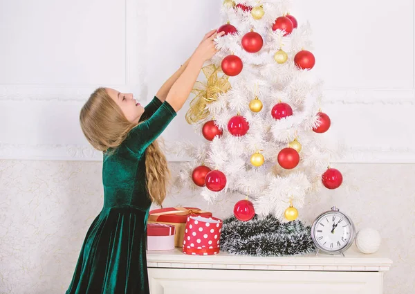 Ребенок вешает рождественский орнамент на искусственное дерево. Дети могут осветить елку, создавая свои собственные украшения. Девочка празднует Рождество. Главная рождественские украшения идеи для детской комнаты — стоковое фото