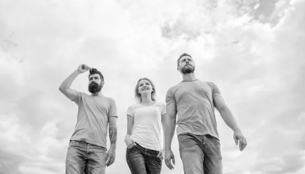 Le grand ajustement pour la journée de congé. Jeunes gens dans un style décontracté sur ciel nuageux. Groupe de personnes en tenue décontractée. Les gens de la mode ont l'air décontractés en tenue d'été. Jolie femme et les hommes amis marchant en plein air — Photo