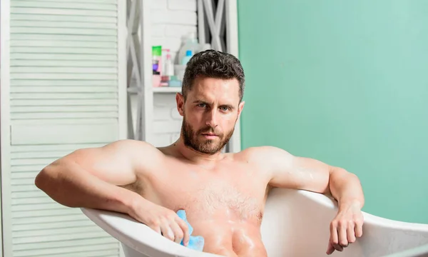 Macho nue dans la baignoire. Laver soigneusement la mousse avec de l'eau. Concept de sexe et relaxation. Macho mec nu attrayant. Homme sexy dans la salle de bain. homme laver le corps musculaire avec mousse éponge. massage détente — Photo