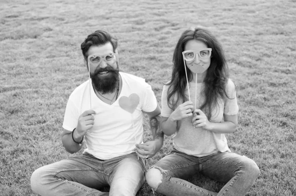 O coração dele pertence-lhe. Homem barbudo a dar-lhe um coração amoroso. Casal apaixonado tendo festa photobooth na grama verde. Mulher sexy e hipster com coração vermelho segurando adereços. Um coração duas almas — Fotografia de Stock