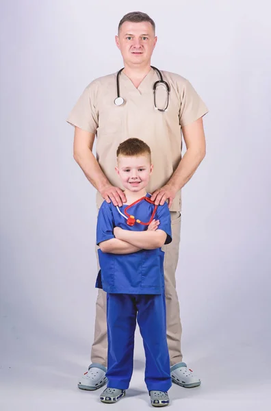 병원에서 아빠와 어린 소년. 아버지와 아들이 의료 복을 입고 있습니다. 청진기를 가진 아버지와 행복한 아이. 가정 의사. 의학 및 건강. 또 다른 근무일. 의사의 병원 팀 — 스톡 사진
