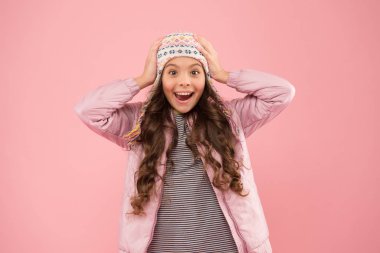 Mutluluk dolu. Soğuk mevsim için sıcak kıyafetler. Örülmüş aksesuar. Küçük kız kış şapkası. Çocuk modası. Moda kızı hipster 'a benziyor. Şaşırmış çocuk pembe arka planı. Sonbahar tarzı. Mutlu çocukluk