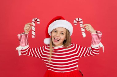 Noel dekorasyonu fikirleri. Dekorasyon dükkanı. Noel dekoru. Kış tatili En sevdiği mevsim. Alışveriş konsepti. Mal al. Çocuk Noel Baba şapkası Noel şekerini kırmızı arka planda tutar.