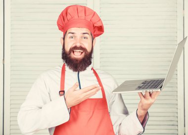 Hipster şapka ve önlük ürünleri online satın almak. Online alışveriş. Teslimat hizmeti. Adam şef yiyecek pişirme online malzemeler arıyor. Market online. Mutfakta şef dizüstü bilgisayar. Aşçılık okulu