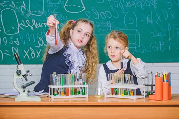 Мы любим науку. Школьные дети проводят эксперименты в классе естественных наук. Маленькие девочки-ученые держат пробирки на уроке естественных наук. Научная лаборатория для школы и образования — стоковое фото