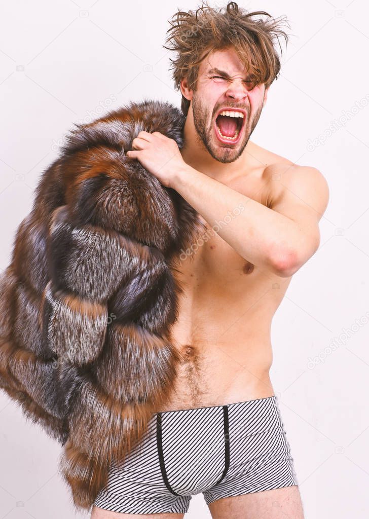 Richness and luxury concept. Bachelor rich lover. Guy attractive posing fur coat on naked body. Luxury lifestyle and wellbeing. Sexy sleepy macho tousled hair isolated on white. Luxury status symbol