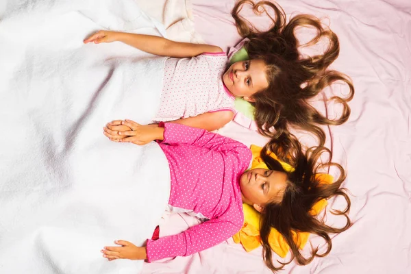 Barn med hjärtan i lös hår ligga på rosa bakgrund — Stockfoto