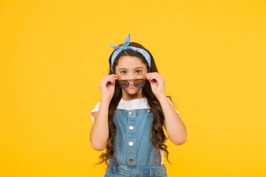 Yaz tatili. Retro çocuk uzun saçı. Küçük çocuk klasik güneş gözlüğü. Tatil modu başladı. Küçük moda düşkünü. Çocuk butiği. Retro kız. Yaz moda konsepti. Neşeli küçük kız sarı arka plan