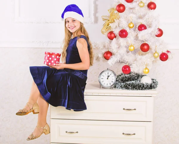 Весела різдвяна концепція. Найкраще для дітей. Дитяча дівчинка біля ялинки тримає подарункову коробку. Дитина святкує Різдво вдома. Маленька дівчинка Санта-капелюх схвильована подарунком. Час відкривати різдвяні подарунки — стокове фото