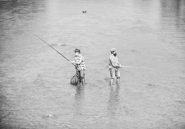 Hobby y actividad deportiva. Pescando juntos. Los hombres están en el agua. La pesca es mucho más que el pescado. Amistad masculina Padre e hijo pescando. Fin de semana. Feliz pescador con caña de pescar y red — Foto de Stock