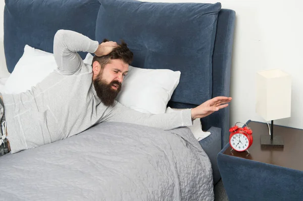 讨厌闹钟的噪音。 头疼得厉害。 男人在家里。 卫生保健概念。 在床上需要更多的放松。 又紧张又不快乐的人。 大胡子的嬉皮士想睡觉。 清早醒来 — 图库照片