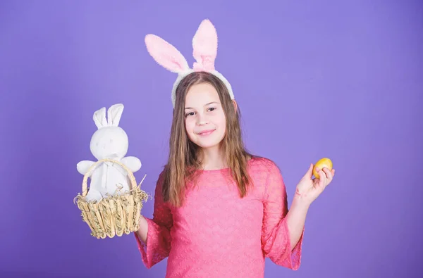 Пасхальне яйце полює як частина фестивалю. Дівчинка, маленька дитина, аксесуар для великодніх кроликів, тримає пофарбоване яйце. Походження великоднього кролика. Великодні символи та традиції. Грайлива дитина з м'якою іграшкою. Зустрічайте весняне свято — стокове фото