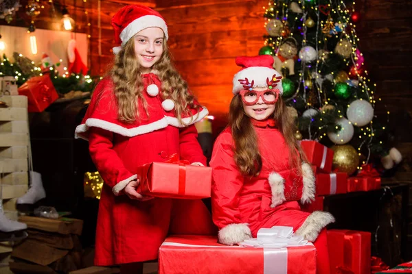 Noel yaklaşıyor. Kırmızı Noel Baba şapkalı küçük kızlar. Noel hediyesini bekle. Mutlu aile yeni yılı kutluyor. Kış alışverişi. Küçük kız kardeşler hediye ister. Yılbaşı zamanı. Kış tatillerini severim — Stok fotoğraf