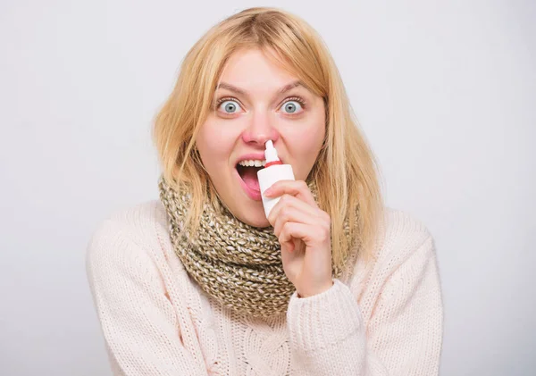 Seasonal allergy. Cute woman nursing nasal cold or allergy. Sick woman spraying medication into nose. Unhealthy girl with runny nose using nasal spray. Treating common cold or allergic rhinitis