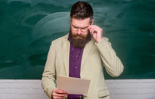 Prepare for test. Teacher bearded man hold documents chalkboard background. Teacher paperwork. School principal. Demanding teacher. Lecturer in classroom. Explaining theory. College and high school