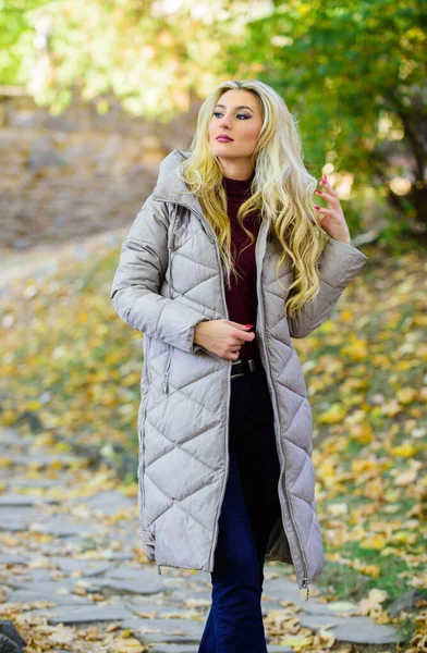 Sonbahar parkında şık sarışın kız yürüyüşü. Kadın kalın gri bir ceket giyiyor. Herkesin alması gereken bir ceket. Büyük boy ceket modası. Yıldız gibi nasıl rock 'çı ceketi giyilir. Puffer moda eğilimi kavramı — Stok fotoğraf