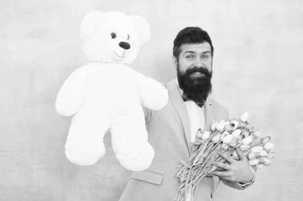 Surprise for her. Man bearded gentleman suit bow tie hold teddy bear and bouquet. Gentleman making romantic surprise for her. Gentleman romantic gift. Birthday greetings. Happy birthday my love — Stock Photo, Image