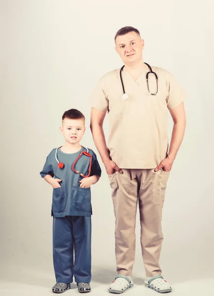İlaç ve sağlık. Babası steteskoplu mutlu bir çocuk. Aile doktoru. Baba oğul tıp üniforması giyiyorlar. Babası hastanede olan küçük bir çocuk. İşine odaklan. Tıp konsepti. tıp erkeği. — Stok fotoğraf