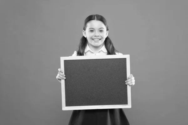 Informer les enfants des changements dans la vie scolaire. Une écolière tient un tableau noir. Concept d'actualités scolaires. Vérifiez les responsabilités des élèves. Sujet de la leçon d'aujourd'hui. Informations sur l'horaire scolaire — Photo