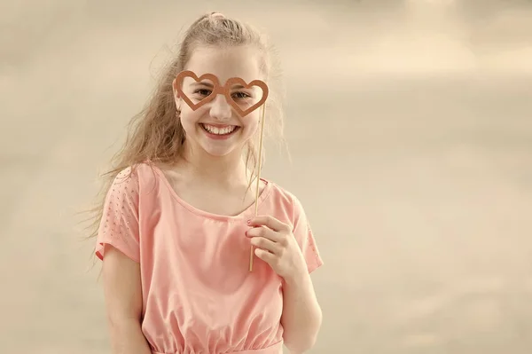 A szemüveg tartozéka az arca. Kisgyerek keres boldog keresztül szemüveg kellékek. Vicces kis lány szív alakú védőszemüveg bottal. Aranyos gyerek mosolyogva divatos fél Googles, másolási tér — Stock Fotó