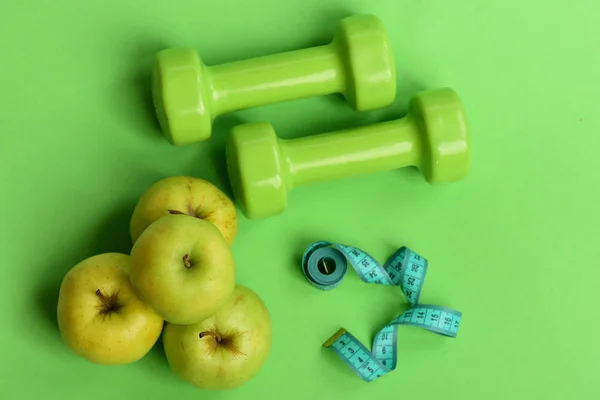 Tape measure in cyan color by barbells and juicy apples — Stock Photo, Image