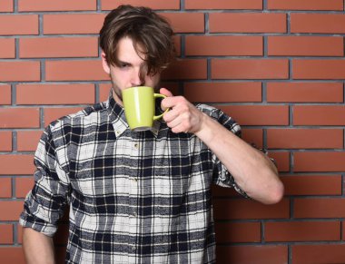 Duvarda fincanı tutan yakışıklı adam.