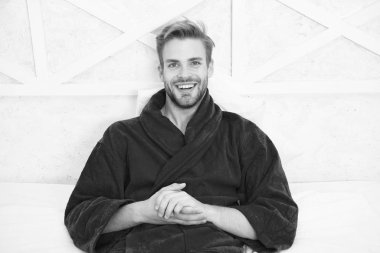 Bornozcu adam rahatlıyor. Uykuya dalmadan önce rahatlamak. Her gece yeterince uyuyun. Genel sağlık için gerekli tutarlı sirkadiyen ritim bakımı. Adam yakışıklı adam yatakta rahatlatıcı