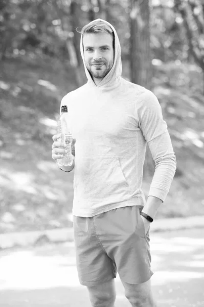 Plný energie. muž v kapuci pije vodu. osvěžení vitamínu po tréninku. atletického muže s vodní lahví. Sportovec pije vodu po tréninku v parku. tělesné hydratace. Sport a zdraví — Stock fotografie