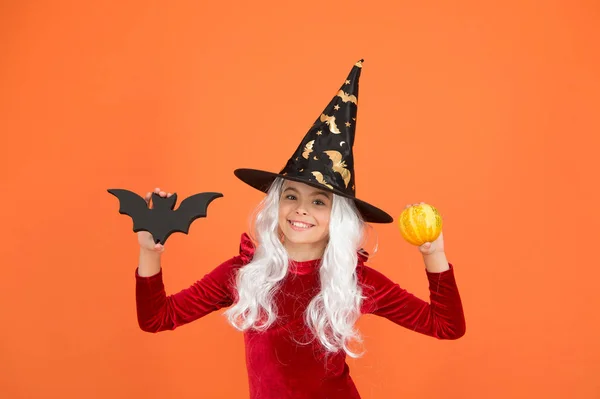 Kılık değiştirmiş gerçek cadı. Mutlu küçük turuncu cadı arka planı. Küçük cadı kız sopa ve bal kabağı tutuyor. Cadılar Bayramı çocuğu cadı şapkasıyla gülümsüyor. Büyücülük ve büyü. Güzel ve gizemli — Stok fotoğraf